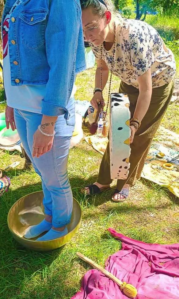 Participante debout pieds nus dans un grand bol tibétain, Priscilla joue du tambour